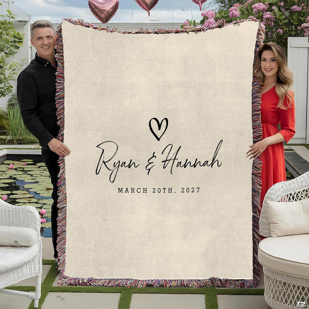 Couple holding minimalist romantic throw blanket with cursive calligraphy, heart motif, and colorful fringed edges