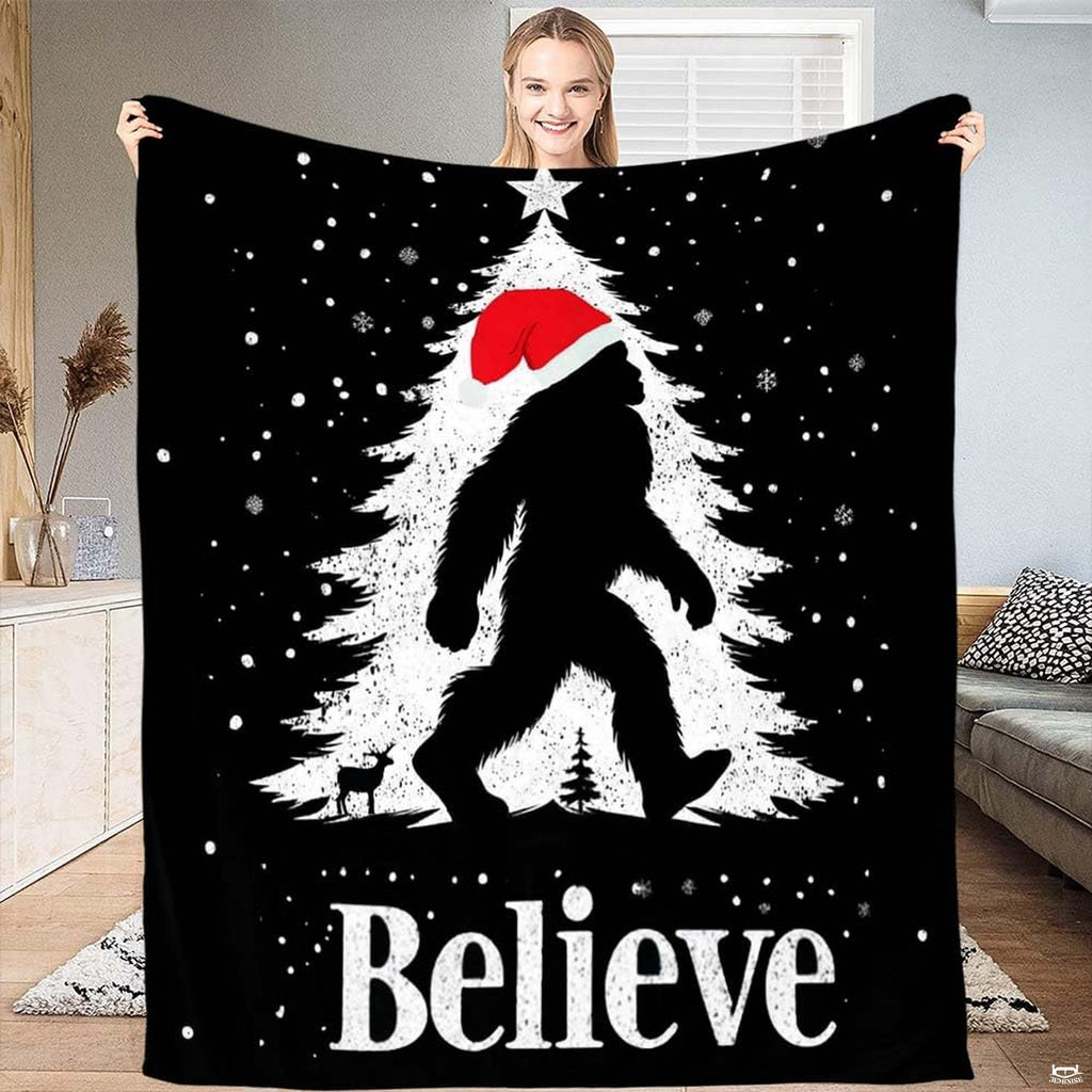 Christmas Bigfoot throw blanket featuring Sasquatch in Santa hat walking past snowy holiday tree with star