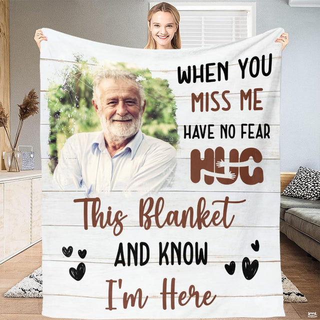 Frontal view of memorial throw blanket displaying an elder portrait on white wood planks with script.