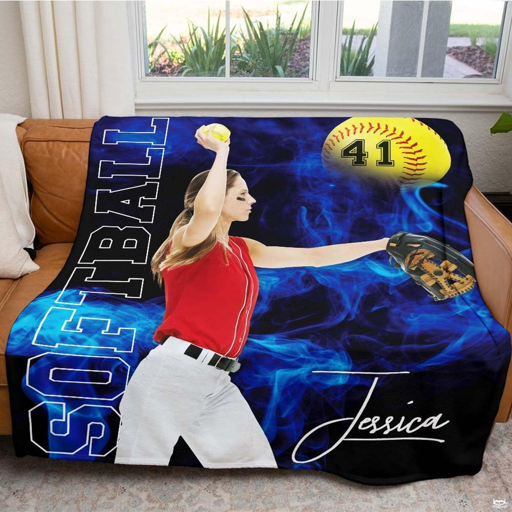Fastpitch sports textile arranged across a brown living room couch facing a window.