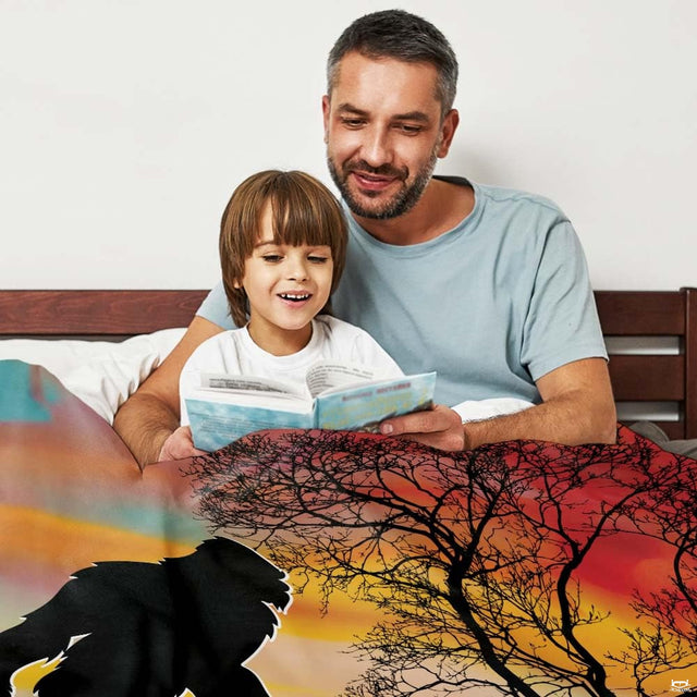 Father and child in bed reading a book covered by rustic Sasquatch sunset blanket