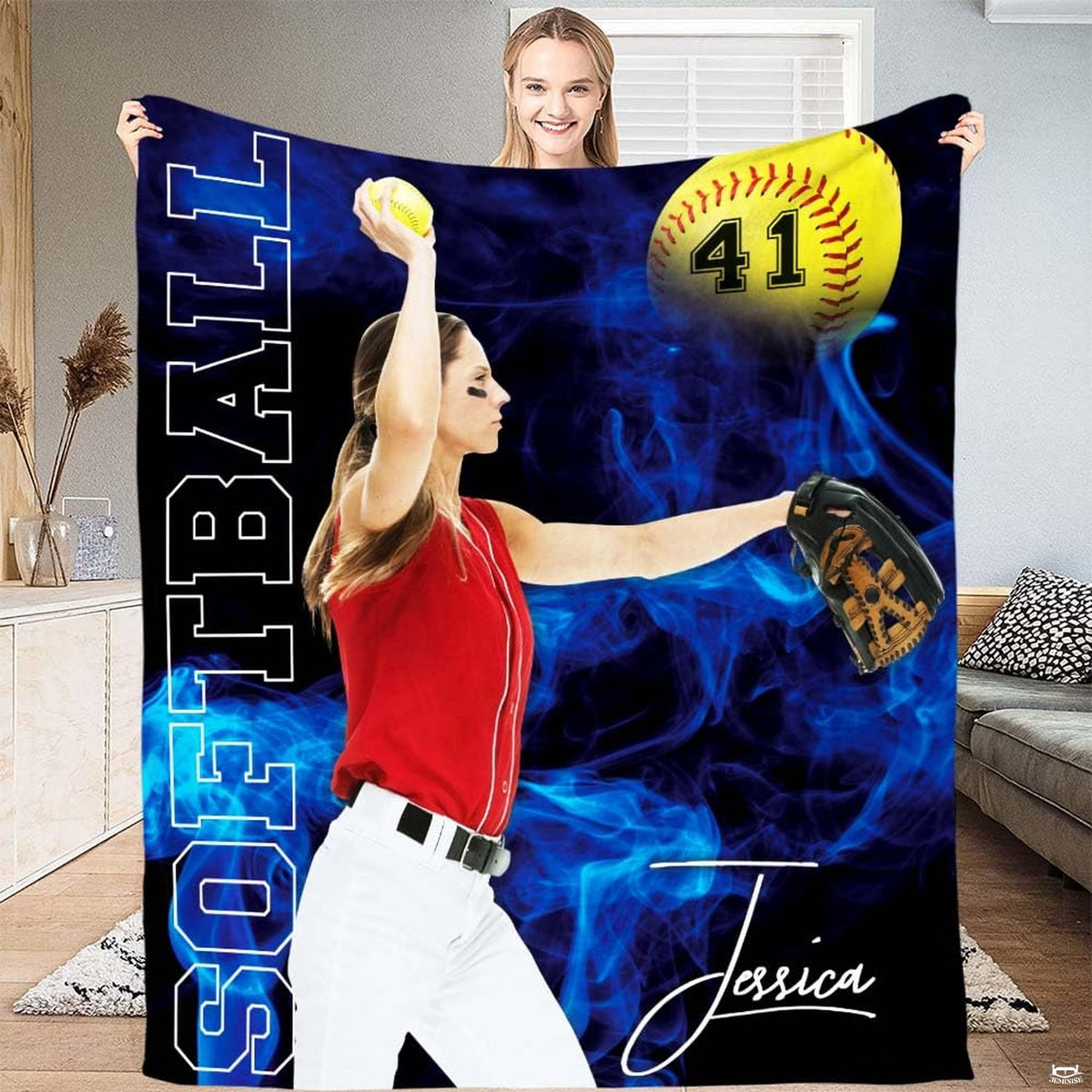 Person standing in bright living room holding up female pitcher sports graphic textile.