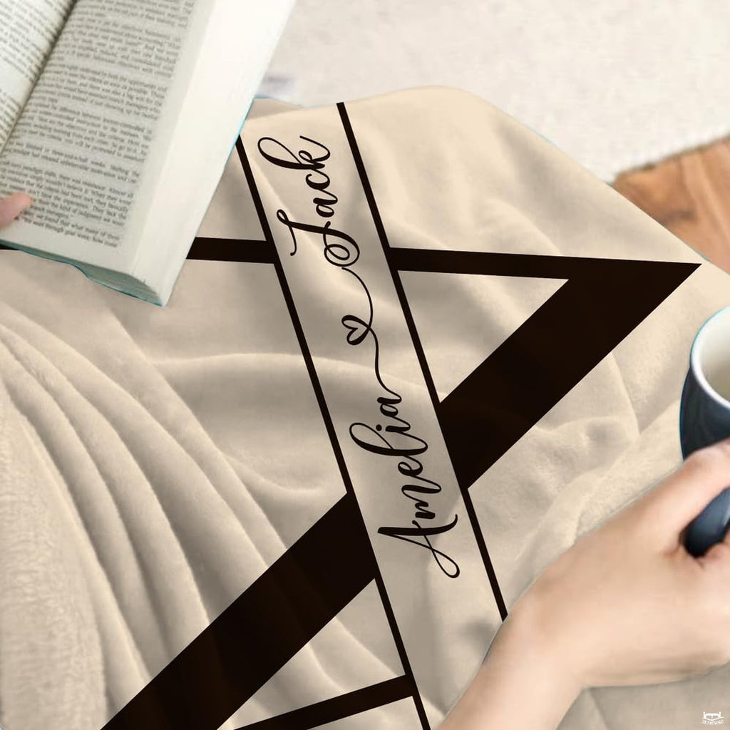Close-up detail of split initial letter and laurel branch artwork on throw blanket