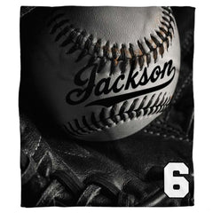 Monochrome studio still-life of a baseball inside a black fielder glove with dramatic lighting, view 1.