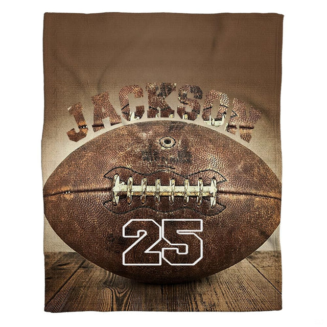 Flat view of vintage football blanket displaying antique ball resting on dark rustic wood planks against sepia backdrop