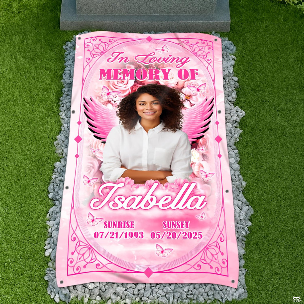Top-down cemetery view showing pink angel wings tribute placed before a headstone on gravel.