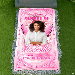 Top-down cemetery view showing pink angel wings tribute placed before a headstone on gravel.