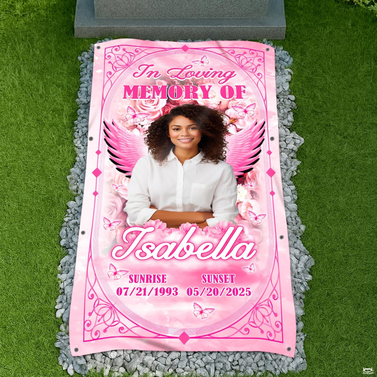Top-down cemetery view showing pink angel wings tribute placed before a headstone on gravel.