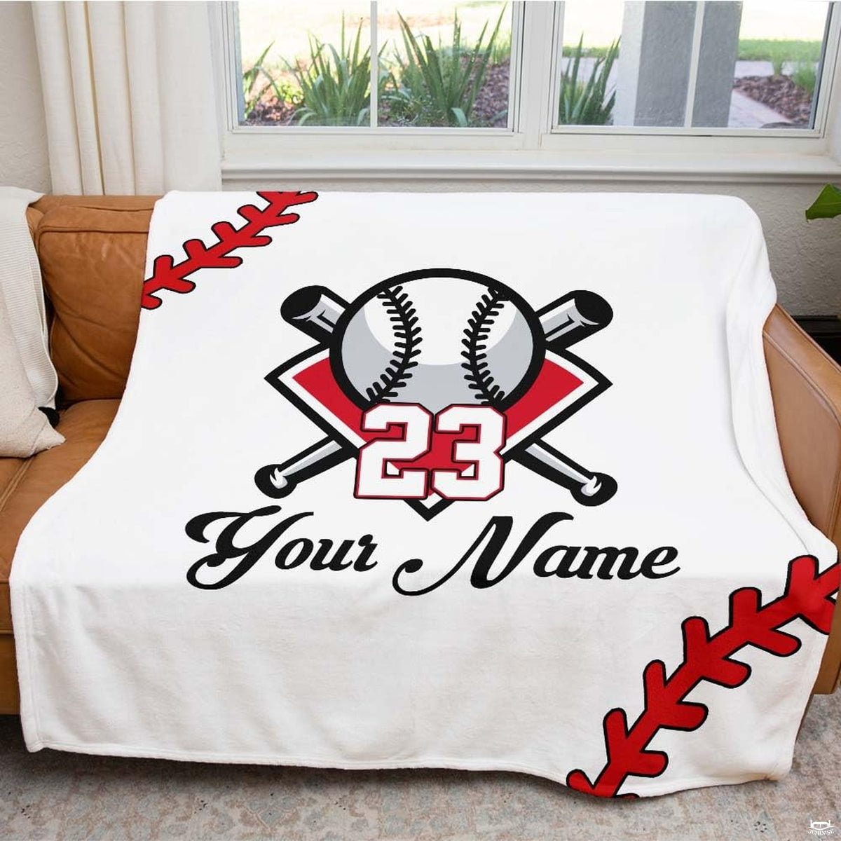 Baseball blanket styled casually over a dark couch corner creating an athletic room accent.