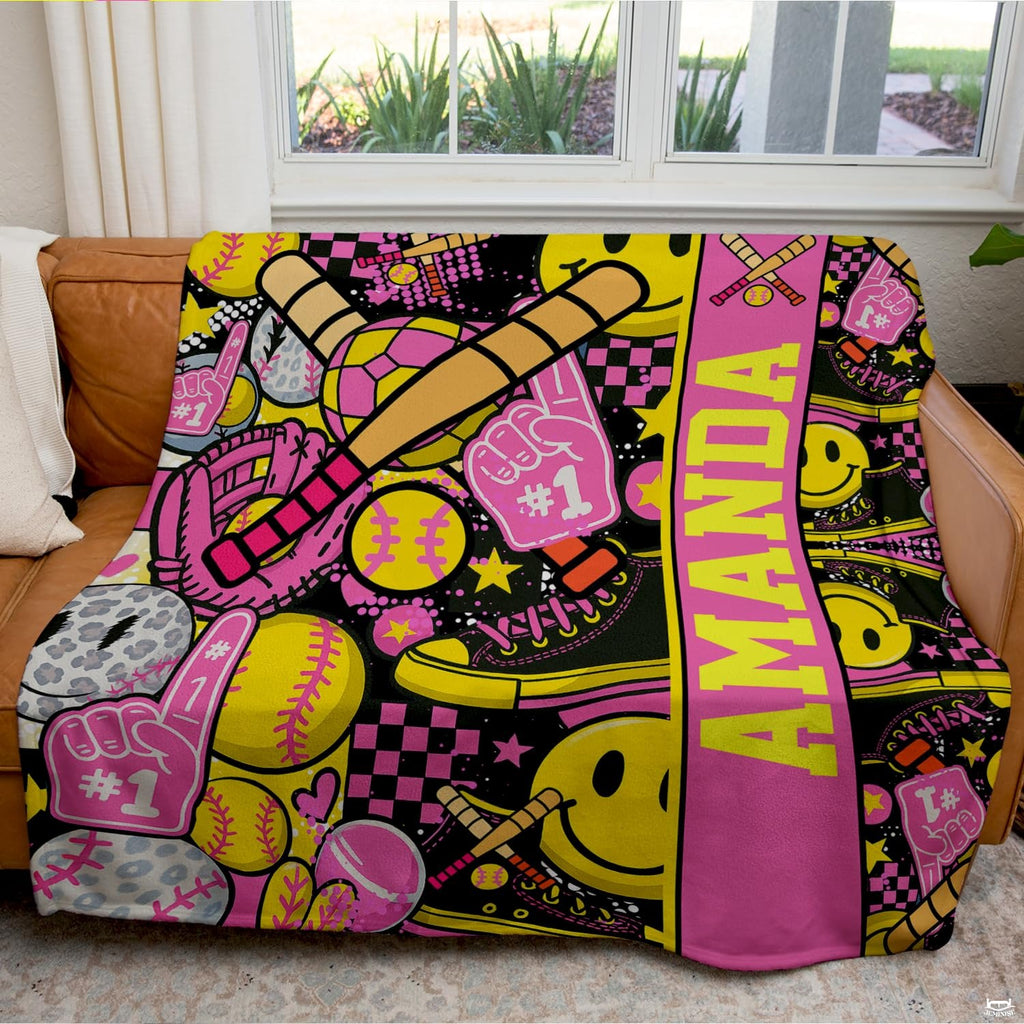 Folded view of pink softball throw blanket showcasing crossed bats and checkerboard prints.