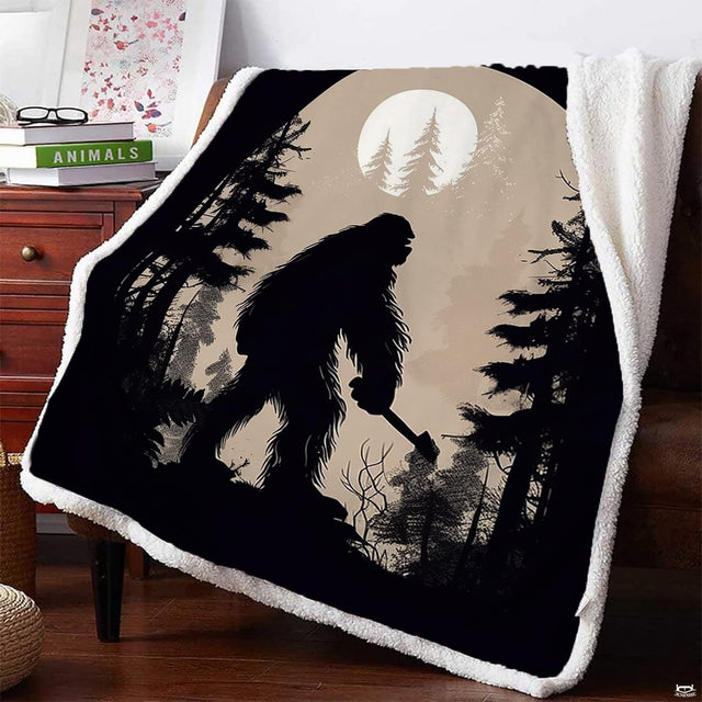 Rustic room setting with a Bigfoot silhouette blanket draped over an armchair next to a wooden nightstand.
