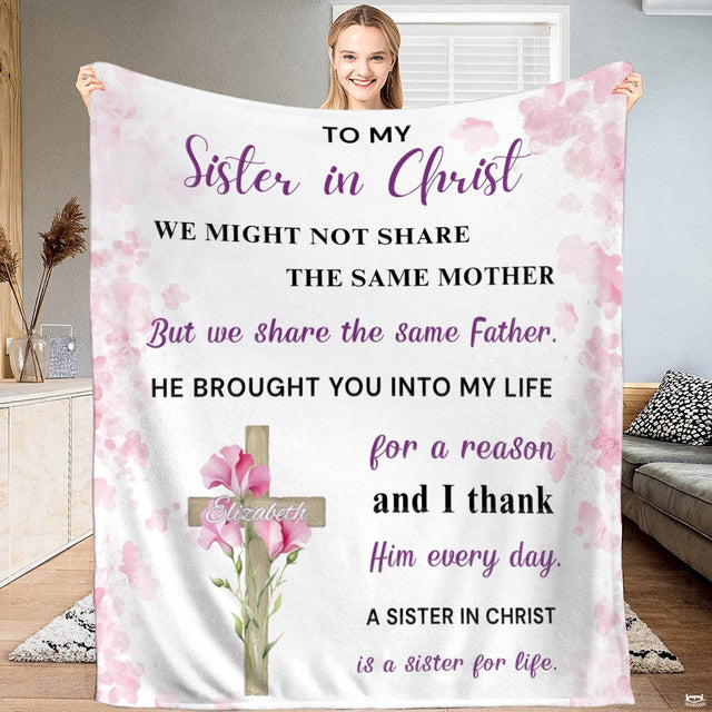 Wooden cross with pink flowers and watercolor border blanket held indoors.
