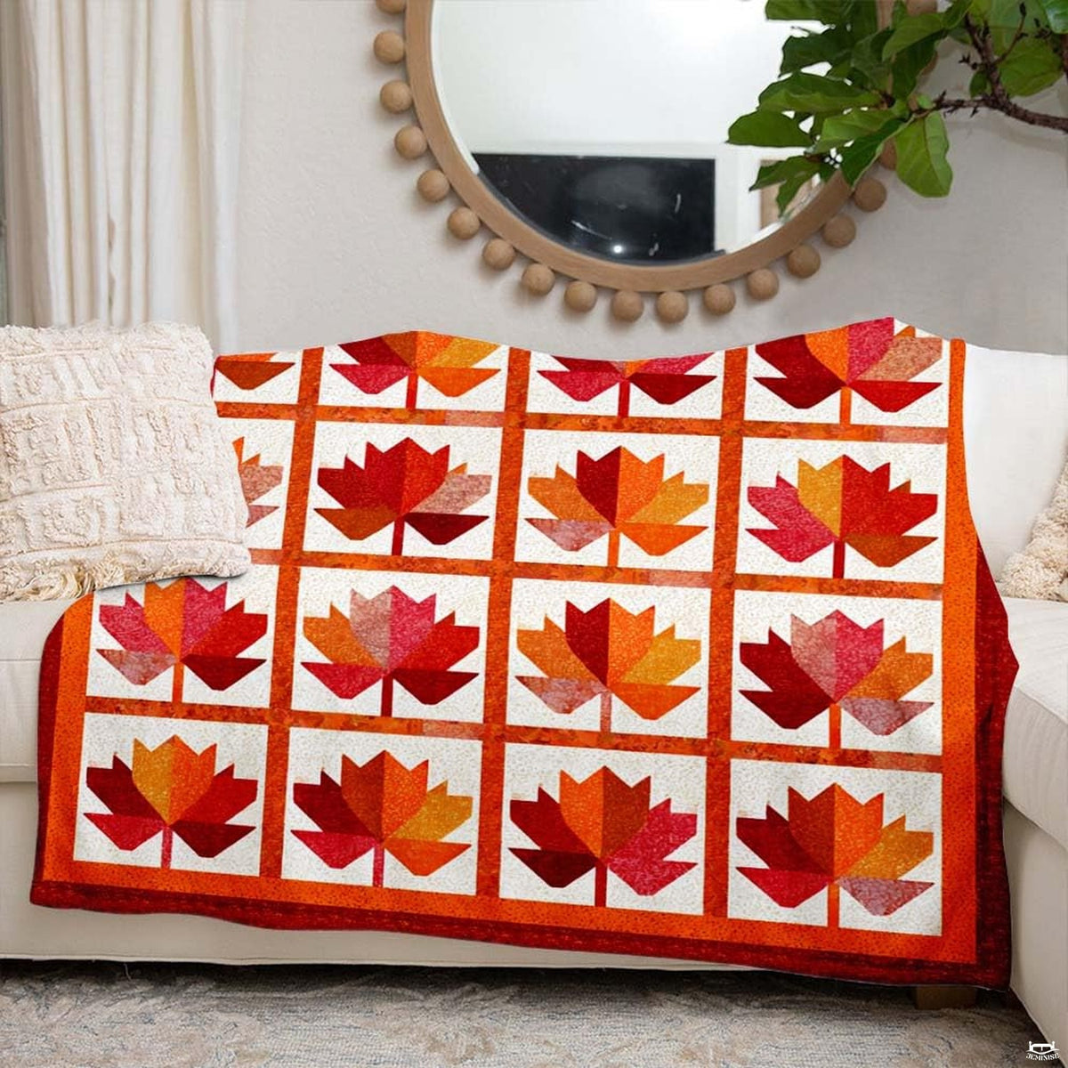Autumn maple leaf blanket styled across a neutral sofa beside seasonal harvest home decor
