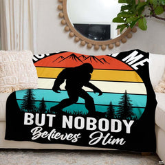 Folded retro sunset Bigfoot mountain throw blanket resting on wooden table displaying sunset print