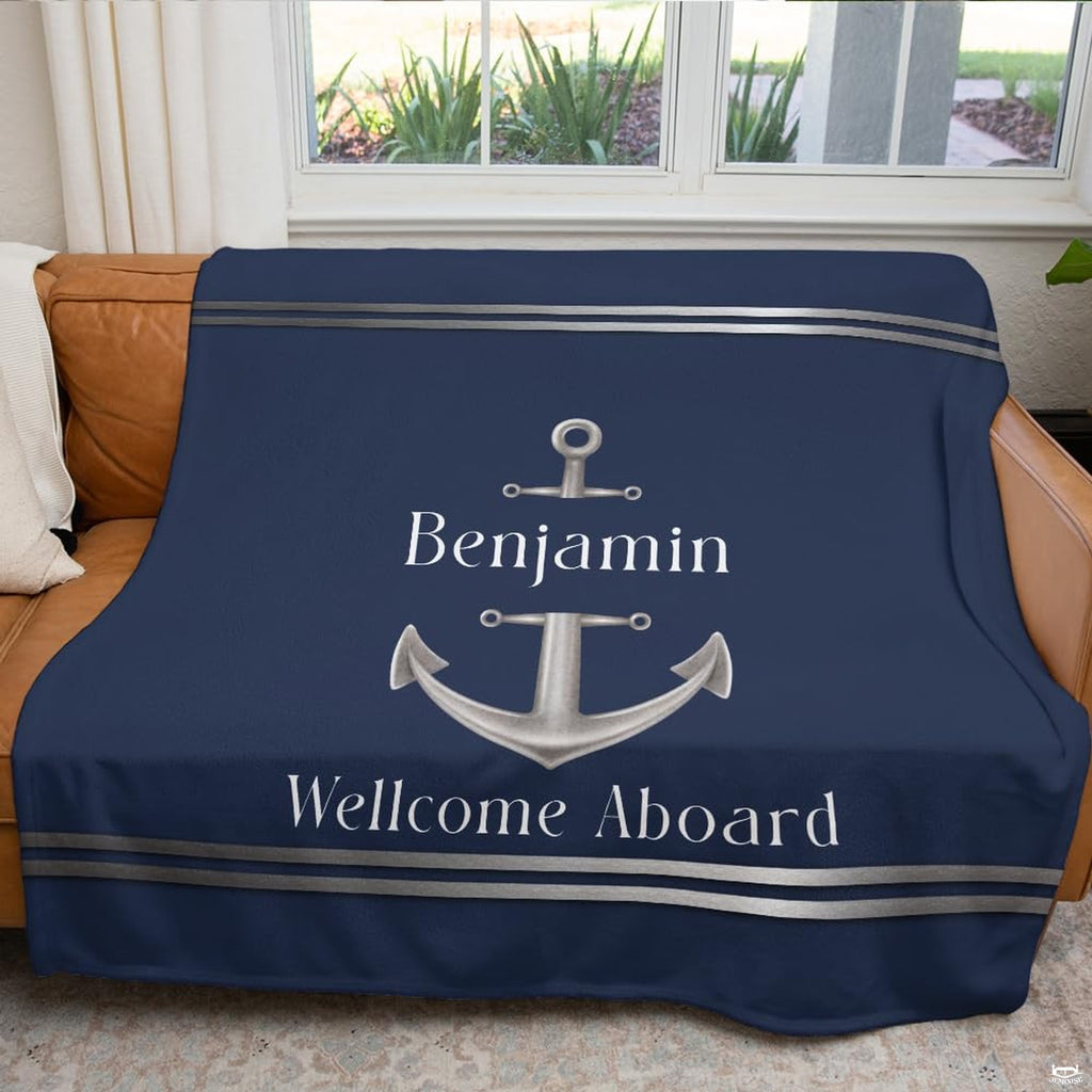 Navy blue anchor print arranged across a couch in front of a bright room window.