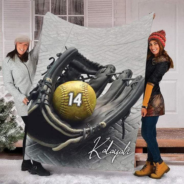 Two people standing outdoors in snow holding up the black softball mitt and ball print.