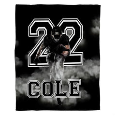 Woman holding open football running back throw blanket showing white smoke clouds and bold typography