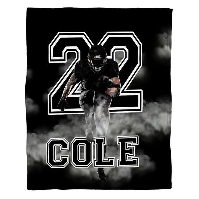 Woman holding open football running back throw blanket showing white smoke clouds and bold typography