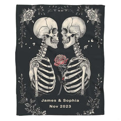 Flat front display of gothic skeleton lovers holding red rose on charcoal.