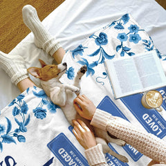 Neatly folded Christian floral throw blanket showing finished edges and porcelain-inspired botanical graphic print