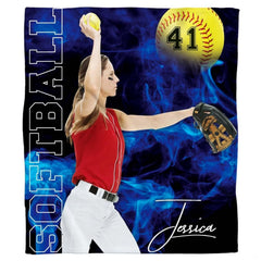 Frontal view of fastpitch pitcher executing pitch amidst electric blue smoke and optic yellow game ball.