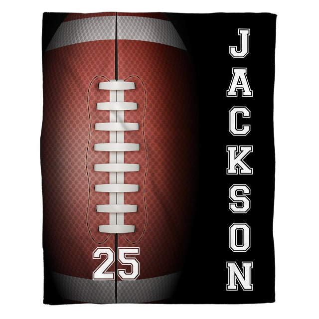 Flat view of football blanket displaying giant textured brown ball, white laces, and black athletic side panel