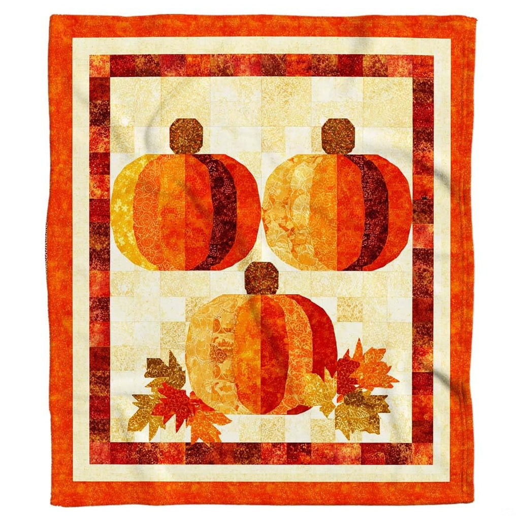 Three quilted patchwork pumpkins throw blanket held open by woman