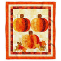 Three quilted patchwork pumpkins throw blanket held open by woman