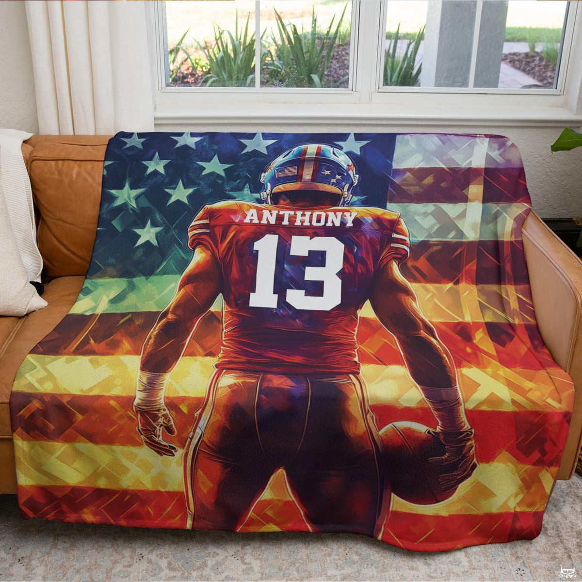 Patriotic football blanket displayed across brown leather couch in bright living room