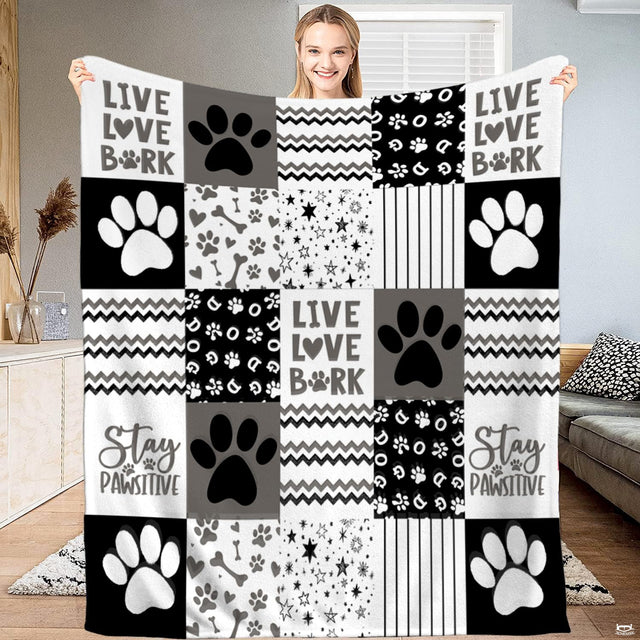 Dog paw print bedding set displaying black and white puppy patchwork art on a bed.