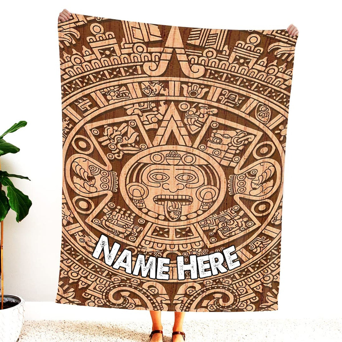 Woman standing indoors holding up carved wood Aztec sun stone graphic textile.