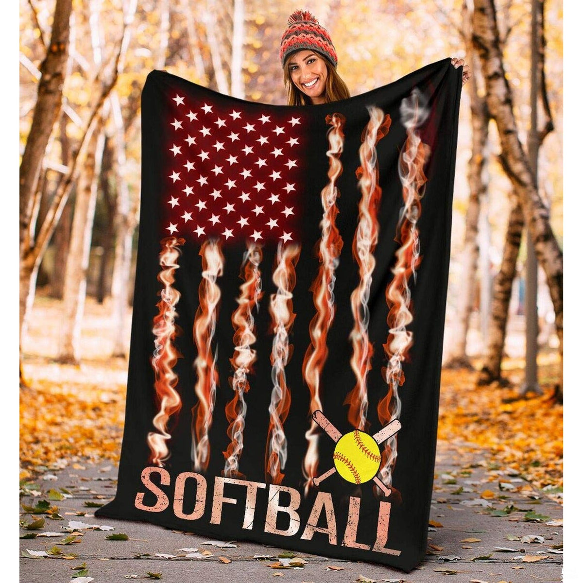 Outdoor autumn setting with woman holding up the fiery flag athletic graphic in a wooded park.