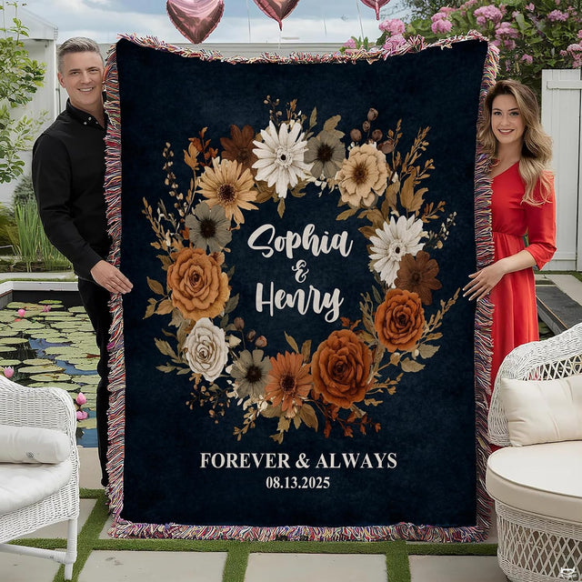 Couple holding autumn floral wreath throw blanket with terracotta roses, script calligraphy, and colorful fringe