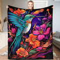 Vibrant hummingbird in mid-flight surrounded by magenta tropical blossoms and turquoise leaves on dark background.