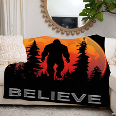 Sasquatch graphic throw blanket displayed neatly over white living room couch beneath round mirror.