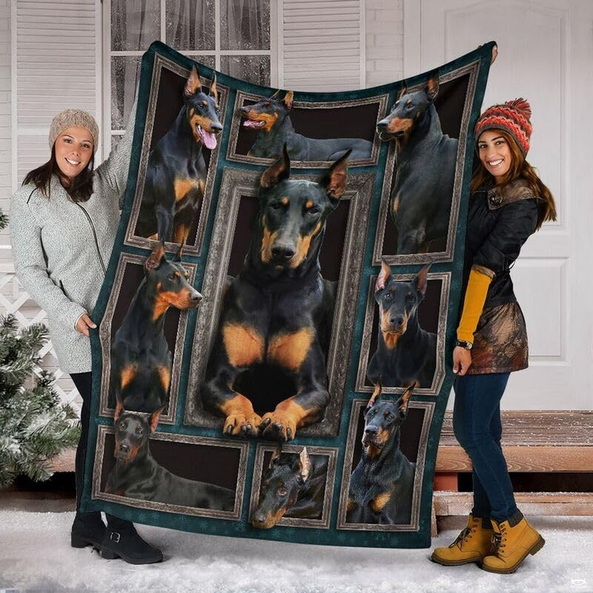 Two models displaying the Doberman Pinscher blanket outside a snowy winter home entrance.