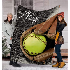 Softball in glove throw blanket held upright outdoors showing lime ball and brown fielder mitt.
