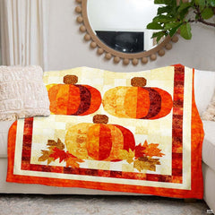 Folded patchwork pumpkin throw blanket on rustic wooden chair
