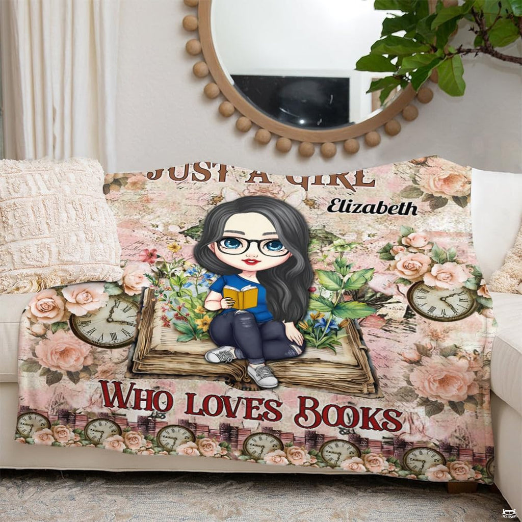 Overhead view of chibi reader artwork surrounded by sage green leaves and blush petals on bedding.