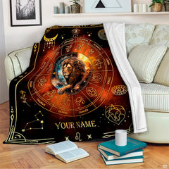 Cosmic zodiac lion blanket draped across an indoor living room couch next to stacked books.