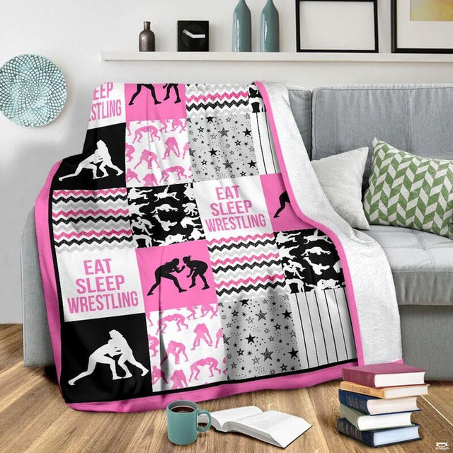 Flat layout of pink and black wrestling blanket displaying athlete silhouettes and chevron patterns.