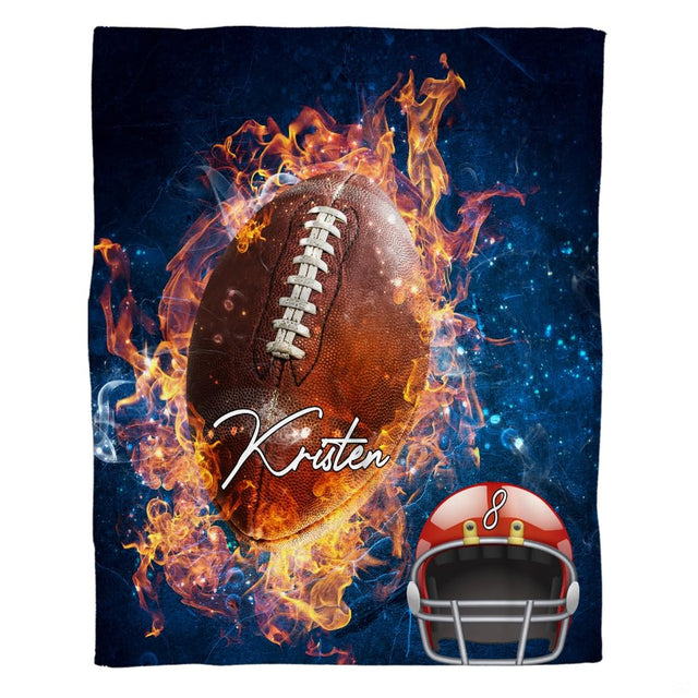 Flat view of football blanket displaying blazing fiery ball and red helmet across starry navy cosmic background
