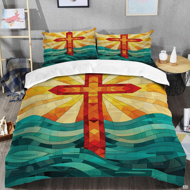 Overhead view of stained glass cross patterns bedding set in bright amber and teal.