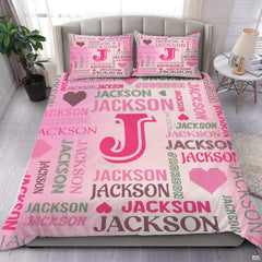 Close-up view of bedding detailing crisp initial outline, pixel heart motifs, and sage green typography accents