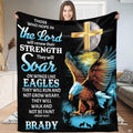 Person standing indoors holding up a decorative Christian cross and flying raptor throw blanket.