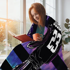 Person relaxing beside window reading with beverage draped in the galaxy football print.
