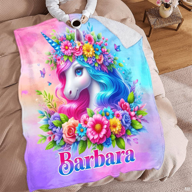 Woman holding open floral unicorn throw blanket showing two-tone pink and cyan mane artwork