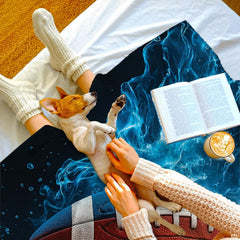 Top-down view of person relaxing under blue water football blanket alongside small dog