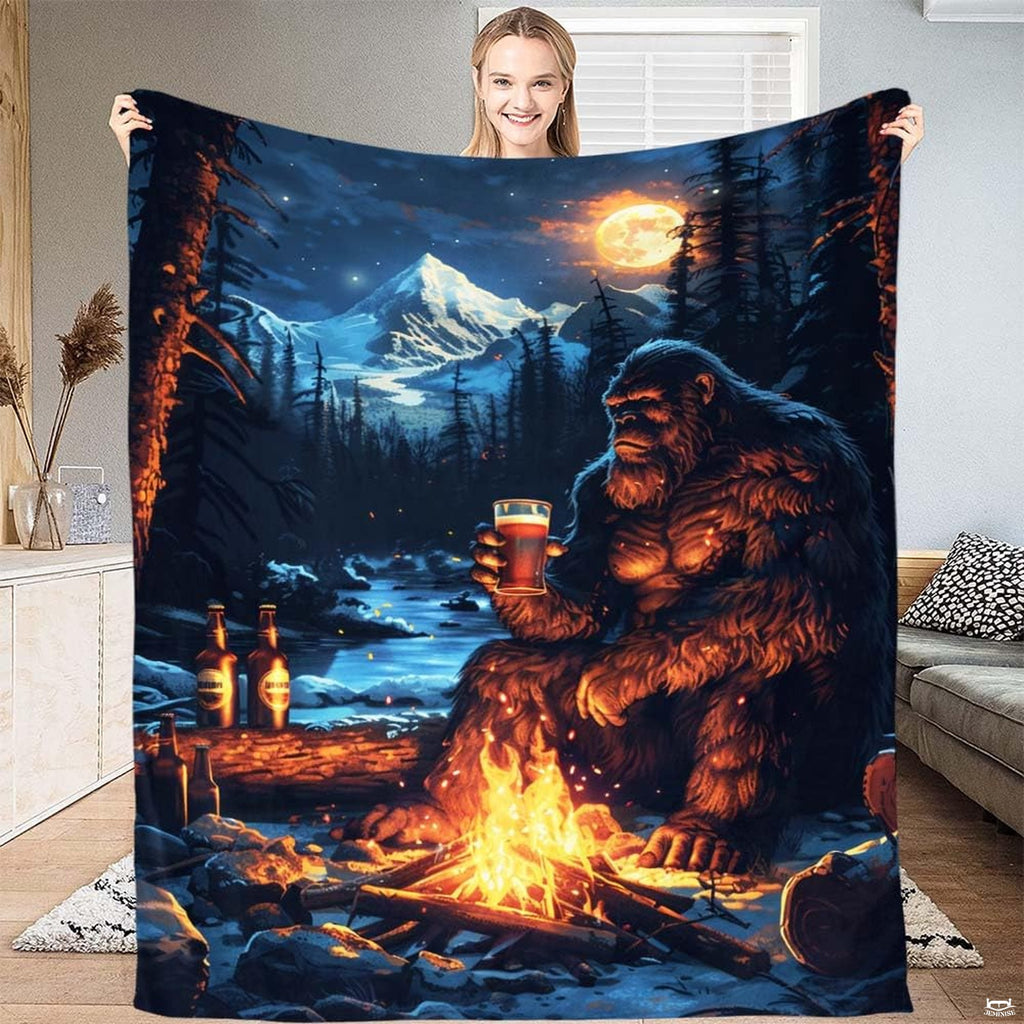 Bigfoot campfire beer mountain throw blanket featuring Sasquatch with drink by fire under alpine moon