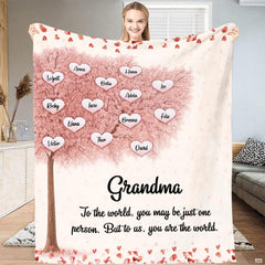 Family tree blanket held up displaying pink cherry blossom tree and heart leaf artwork